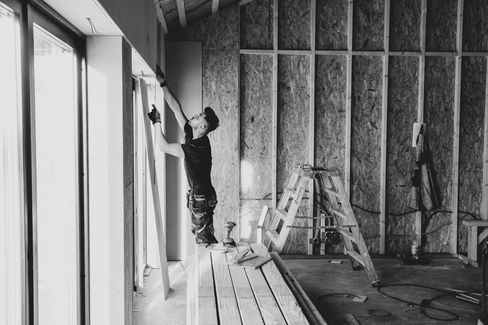 Monteur zet een plaat rechtop tegen een wand in een ruwbouw.
